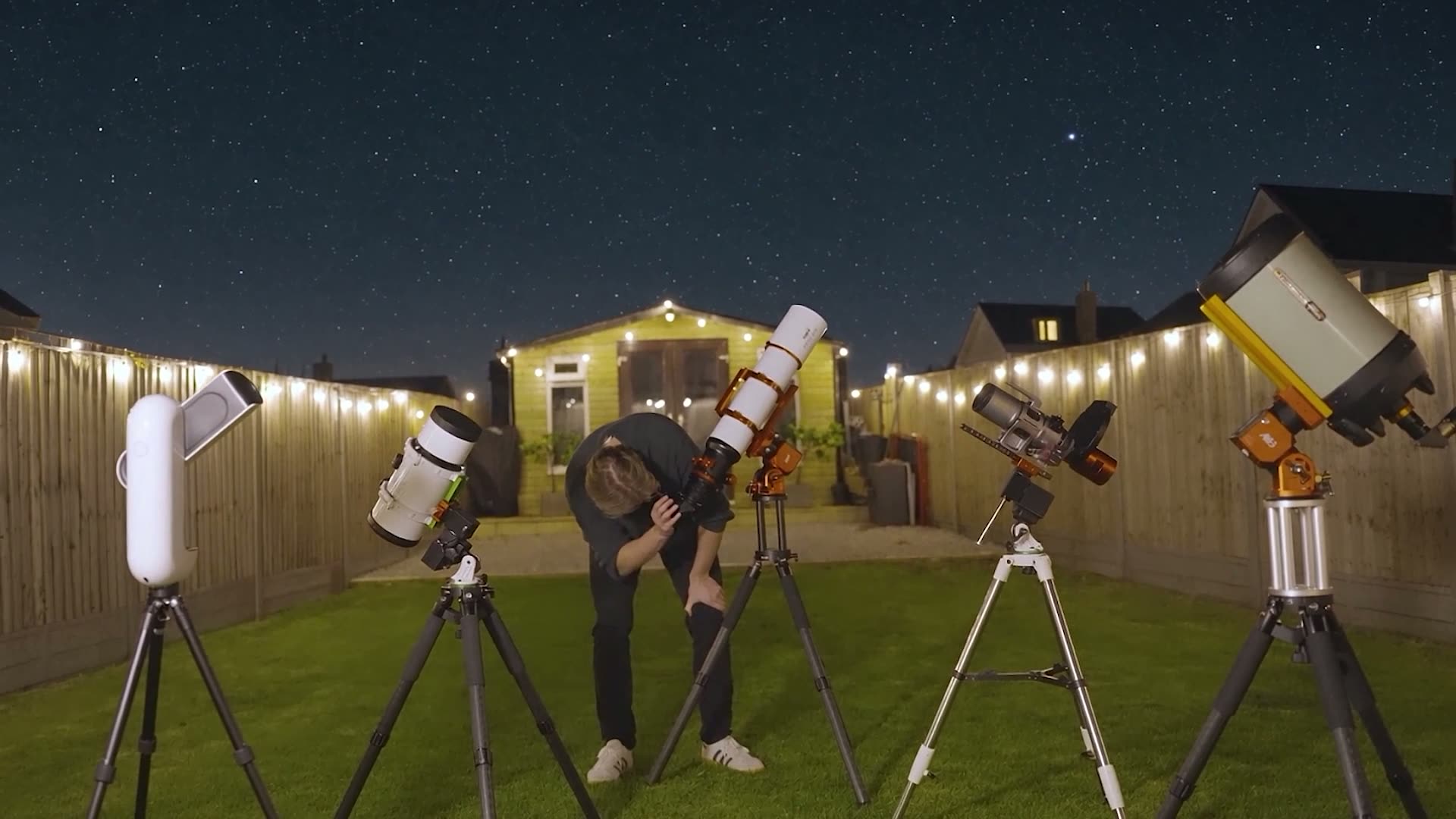 Damon Scotting at the eyepiece of a telescope in his garden at night, among his telescopes